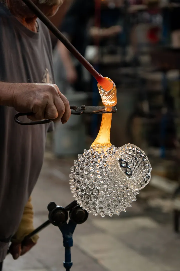 Sklář kleštěmi tvaruje ucho na žhavém džbánu Hobnail
