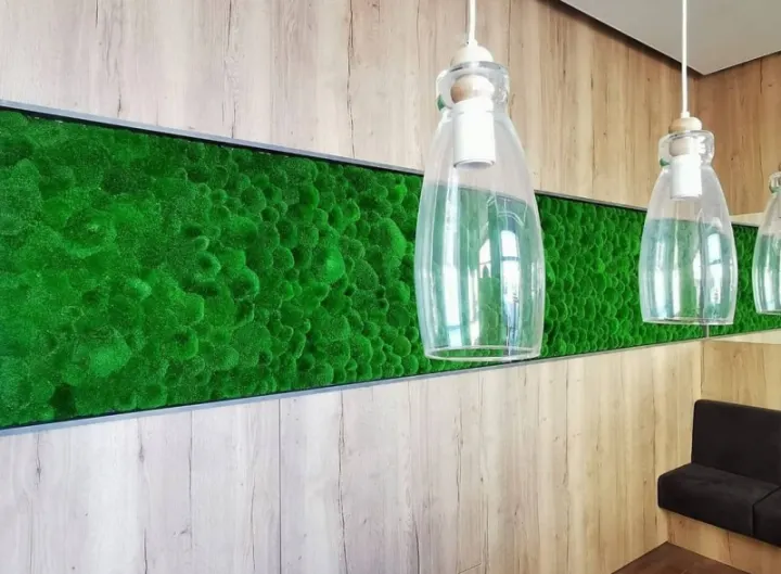 Pás z mechu mezi dřevěnými panely se skleněnými závěsnými lampami v restauraci