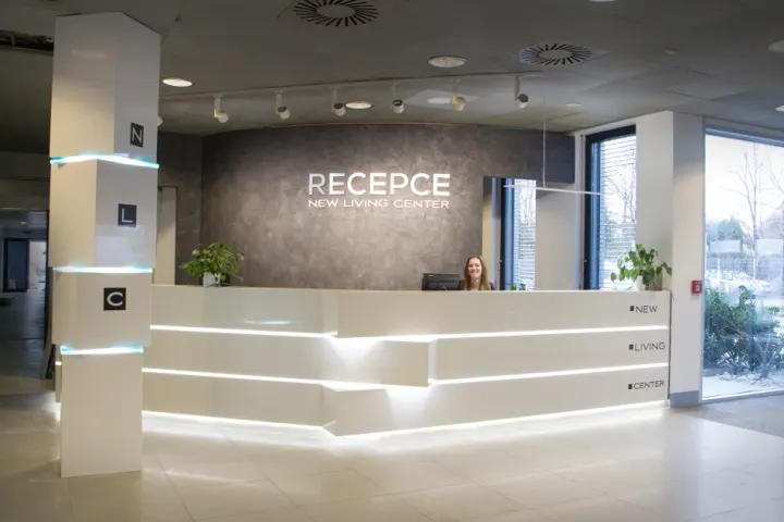 Podsvícený recepční pult a obložený sloup v obchodním domě New Living Center v Praze